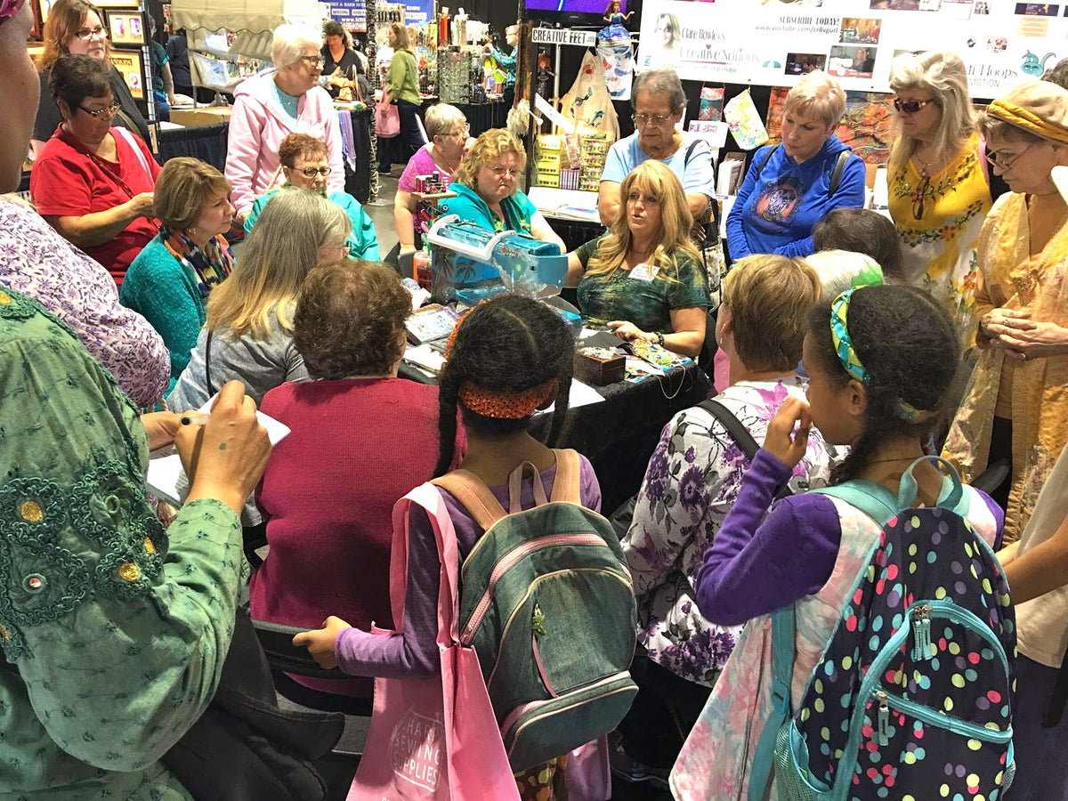 Creative Feet booth at a sewing & quilt show in Tucson, Arizona. Clare Rowley demonstrating to a large crowd.